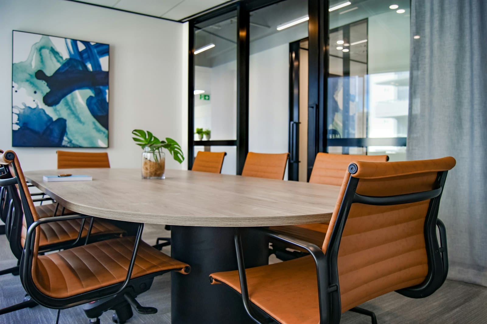 Orderly meeting table with tan leather chairs in a glass-walled office