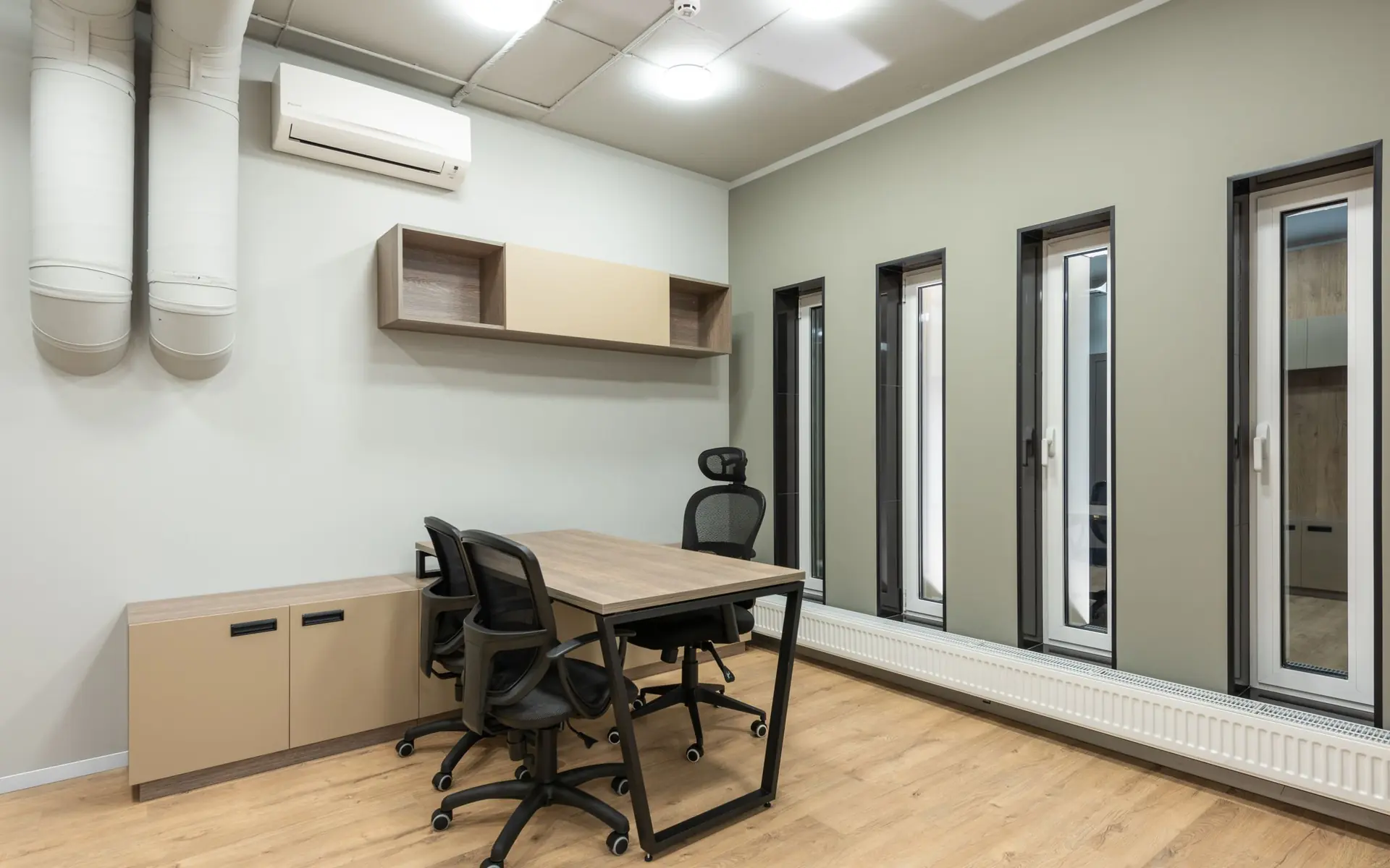 Modern office with desks, chairs and tall windows.